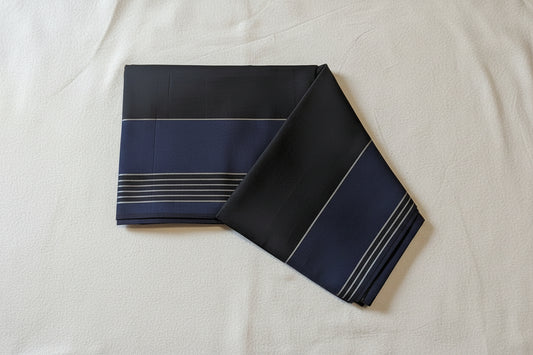 Folded black fabric with blue stripes on a beige surface